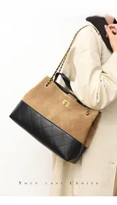 Detail of quilted leather tote bag with gold twist lock and chain strap on shoulder