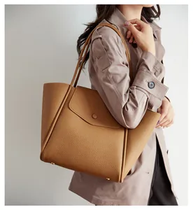Dettaglio della borsa tote in pelle cammello con patta e piedini metallici protettivi