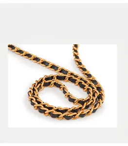 Detail van glijdende gouden ketting en zwart leren riem voor een gewatteerde emmerzak