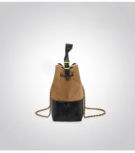 Detail of brown suede bucket bag with black quilted leather and gold chain strap