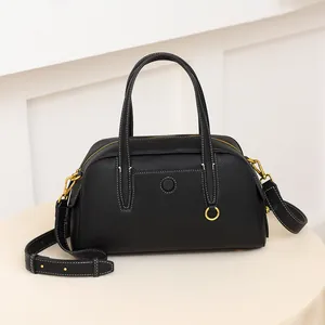 Detalle del bolso de cuero lichi negro con costuras blancas y herrajes en tono dorado