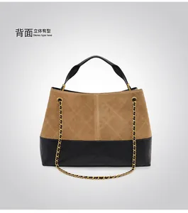 Detail view of contrast paneled handbag with black quilted leather and tan suede finish