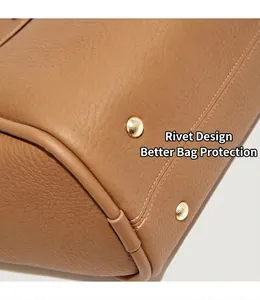 Dettaglio del fondo borsa in pelle martellata con rivetti metallici dorati protettivi
