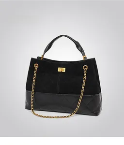 Detail of black quilted leather stitching with gold metal turn-lock and chain strap