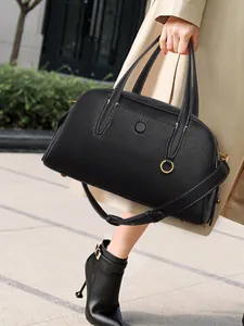 Detalle de bolso negro de piel granulada con herrajes dorados y asas de alta calidad