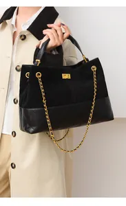 Detail van zwarte gewatteerde emmertas met gouden ketting en draaisluiting op model