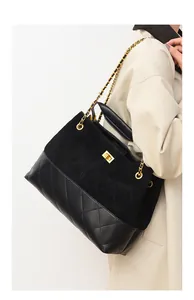 Detail of black suede and quilted leather handbag with gold chain strap and metal clasp