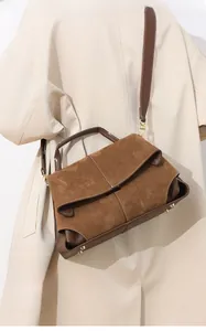 Detailed macro view of the brown suede and textured leather splicing on a luxury handbag