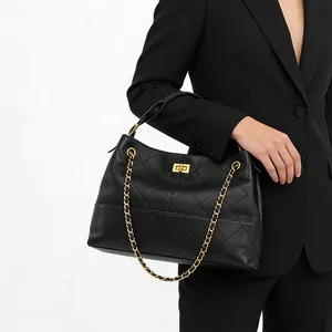 Detail of black quilted leather shoulder bag with gold square twist lock and chain strap