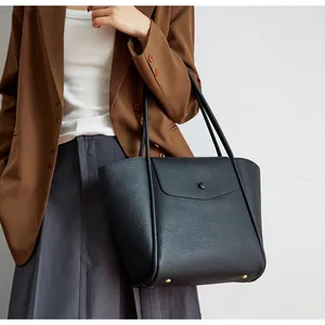 Dettaglio della borsa tote in pelle nera con piedini protettivi dorati e grana fine