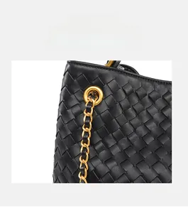 Detail of black woven leather texture with gold metal eyelets and chain strap