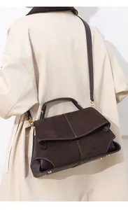 Detail of dark brown suede and leather tote bag featuring white contrast stitching