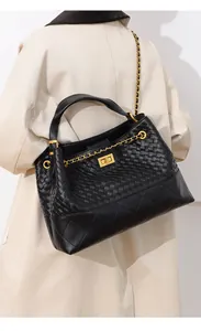 Close-up of black leather woven bucket bag with quilted patterns and gold chain strap