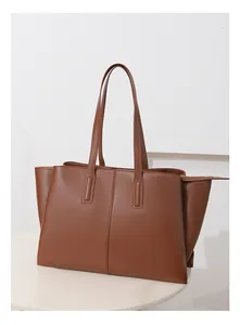 Detail of a large brown leather tote bag with vertical stitching and metal zipper on white