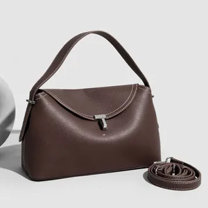 Detail of dark brown lychee leather handbag with white stitching and silver T-shaped buckle