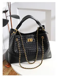 Detail of woven and quilted black leather tote with golden twist-lock and chain straps