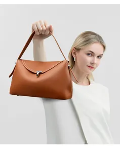 Close-up of caramel leather handbag with white stitching and textured litchi grain