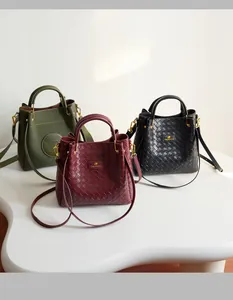 Trois sacs seaux élégants à texture tressée en vert foncé, bordeaux et noir sur un support blanc