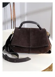 Detail of dark brown suede handbag featuring white contrast stitching and gold hardware