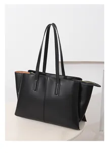 Macro view of matte black leather tote bag with gold zipper and stitching details