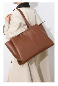 Detailed side view of large brown leather tote bag with vertical stitching on shoulder