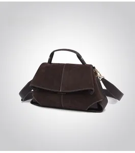 Detail of dark brown leather handbag with suede flap, contrast stitching and gold hardware
