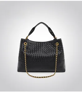 Detail view of black woven and quilted handbag with a gold-tone metal chain handle