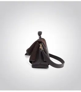 Detail of dark brown matte leather handbag featuring golden hardware and detachable strap