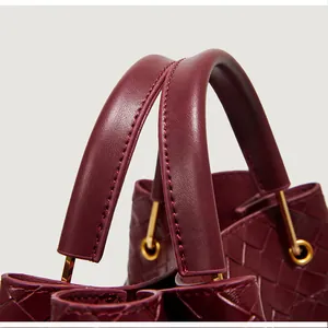 Gros plan sur la texture en cuir tressé bordeaux avec détails métalliques dorés fins