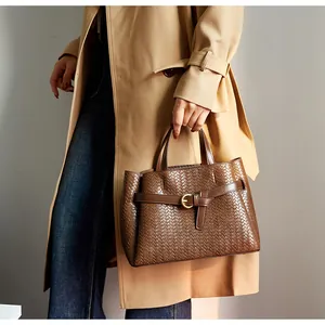 Detail of woven brown leather tote bag showing intricate texture and golden buckle strap