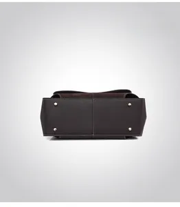 Detail view of leather handbag base with protective gold studs and contrast stitching