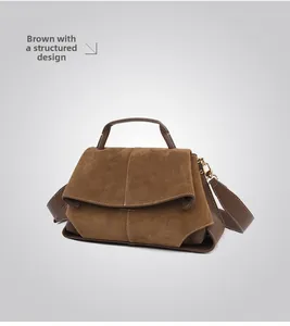 Detail of a brown matte leather handbag featuring golden hardware and a wide shoulder strap