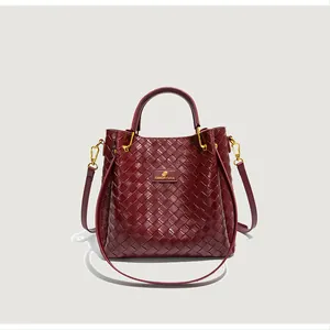 Gros plan sur la texture tressée bordeaux du sac seau avec détails métalliques dorés