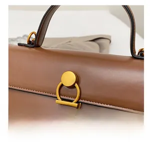 Détail du cabas en cuir grainé marron avec boucle décorative en métal doré mat élégant