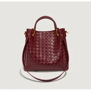 Détail du sac seau en cuir tressé rouge foncé avec des boucles métalliques dorées