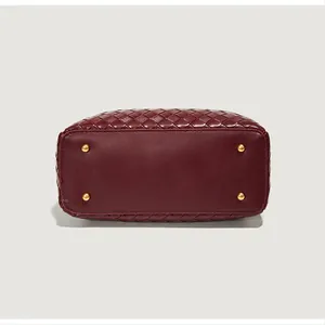 Détail du fond d'un sac en cuir tressé bordeaux avec pieds de protection dorés