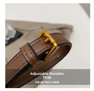 Gros plan sur la bandoulière réglable en cuir marron avec boucle en métal doré et coutures