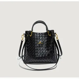 Détail du tissage noir sur sac seau avec boucles dorées et plaque de logo en métal