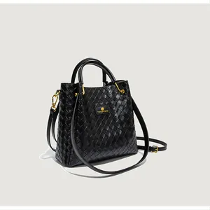 Gros plan du sac seau tressé noir montrant la texture et les ferrures dorées brillantes