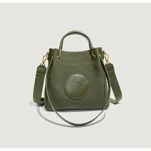 Détail du sac seau vert olive avec texture gaufrée serpent et ferrures métalliques dorées