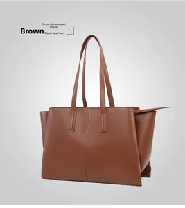 Detail view of large brown faux leather tote bag with vertical stitching and sturdy handles