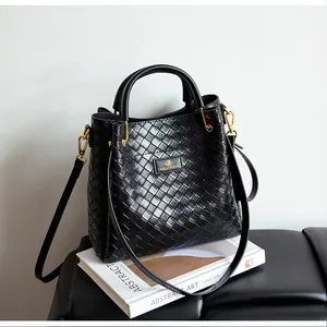Détail du sac en cuir tressé noir avec ferrures dorées et plaque de logo de la marque