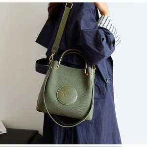 Gros plan du sac seau vert montrant le cuir gaufré texturé et les finitions dorées