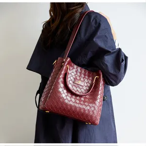 Gros plan du sac cabas bordeaux à texture tressée avec détails en métal doré