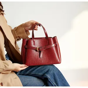 Close-up of deep red woven tote bag featuring a decorative belt buckle and high-end texture