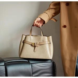 Close-up of beige woven texture tote bag featuring gold hardware and dual top handles
