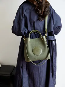 Sac seau vert olive avec texture serpent et large bandoulière porté par un mannequin