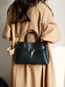 Women's black woven leather tote bag with gold hardware shown on a trench coat model