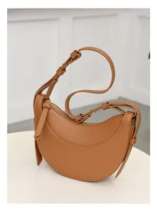 Detalle del bolso de media luna caramelo con textura granulada y cremallera dorada