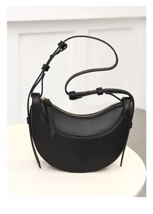 Detalle de bolso media luna en piel Saffiano negra con correa y cremallera dorada